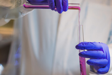 A woman scientist adding Organic reaction in test tubes in a laboratory.