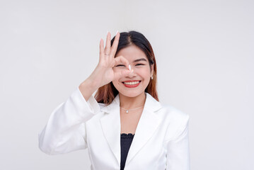 A happy young woman making okay gesture with her hand and peeking at it. Isolated on a white background.