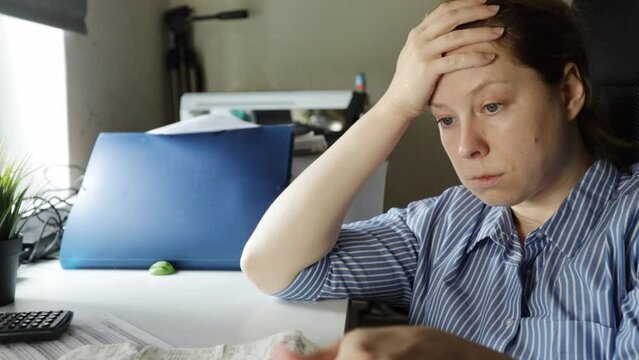 a woman counts taxes and financial expenses, holding her head, unprofitable business, poverty, financial crisis