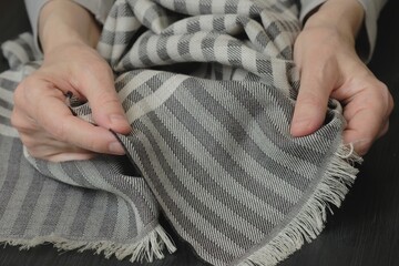The scarf is striped gray. A new silk scarf is in women's hands. Demonstration
of accessory design elements, pattern and method of weaving fabric threads.
