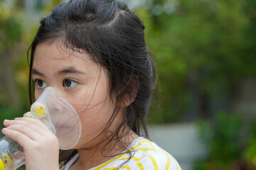 Cute asian girl with asthma using inhaler and spacer,Respiratory system and allergies - obrazy, fototapety, plakaty