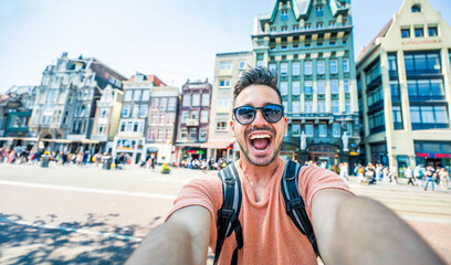 Happy tourist taking selfie picture in Amsterdam, Netherlands - Cheerful man using smart mobile...
