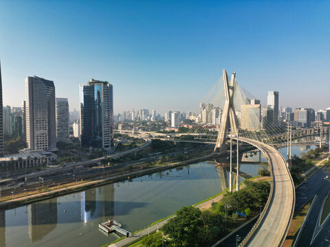 2023 view of the Pinheiros river with modern buildings beside it and the famous Octavio Frias de Oliveira bridge in the city of S&atilde;o Paulo.