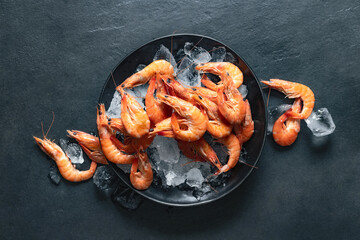 Healthy food. Fresh shrimps with ice close-up on plate on dark background top view