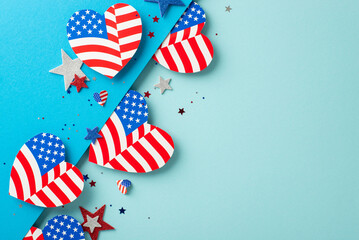 Veterans Day USA imaginative celebrations. Top view of patriotic adornments: hearts decorated with American flag pattern, glittering stars, confetti on bicolor blue surface with space for text or ad