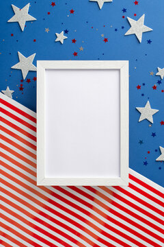 Celebrate spirit of Independence Day. Vertical top view showcases allure of symbolic adornments: stars, luminous confetti, photo frame on American flag background with space, ideal for text or picture