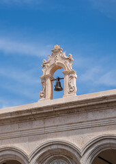 Old rustic ornate bell atop a classically designed building.