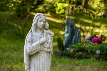 Statue Jungfrau Maria mit Kind vor Grab am Friedhof