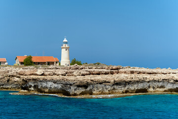 Horizontal view from sea to lighthouse on the rock. Landscape with turquoise sea water