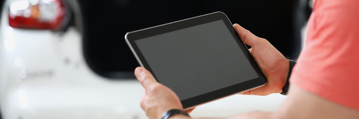 Rear view of worker holding tablet and checking machine. Auto mechanic with tablet and applications...
