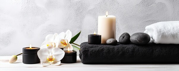 Obraz na płótnie Canvas Beauty treatment items for spa procedures on white wooden table and marble wall. massage stones, essential oils and sea salt. candle, rolled up white towel, plants, copy space