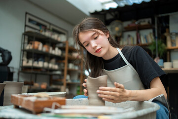 Beautiful young woman holding pottery instrument for scraping.