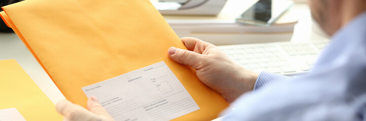 Businessman holding yellow package with mail in office. Delivery or mailing business mail concept
