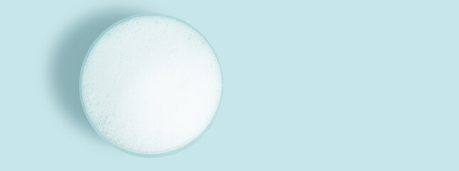 Washing agent foam in a Petri dish. On a blue background.
