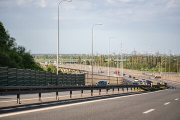 Fototapeta na wymiar Gdansk, Poland - May 26, 2022: Cars on the highway. Expressway in the rays of the setting sun. Asphalt Ribbon.