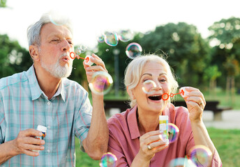 woman man senior couple  together elderly active happy retirement bubble soap blowing fun blow...