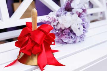 Close-up of a bell with a red ribbon. The celebration of the last bell at school.