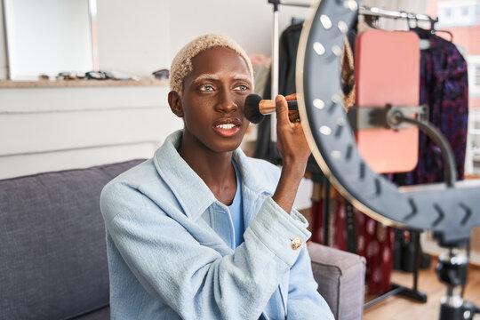 Blonde online content creator applying a makeup on - Powered by Adobe