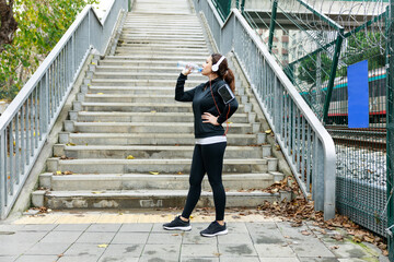 Young sports woman drinking from water bottle