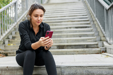 Young athletic woman using her smart phone before working out