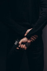 Close up of male hands holding aiming gun on a black background.