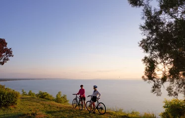 Foto op Canvas Two women with bicycles on the sea or lake shore © luengo_ua