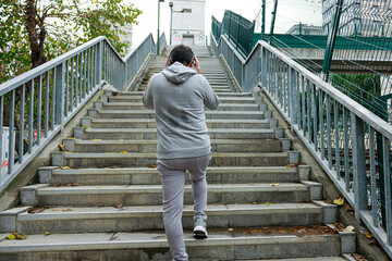 Young man with headphones walking toward upstairs. Sport, fitness and healthy lifestyle concept