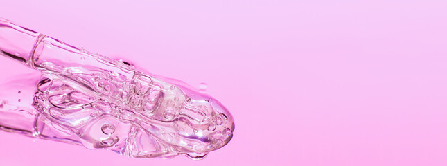 Spilled transparent golden yellow bubbly gel close-up. Leaking out of the pipette.  In pink tones