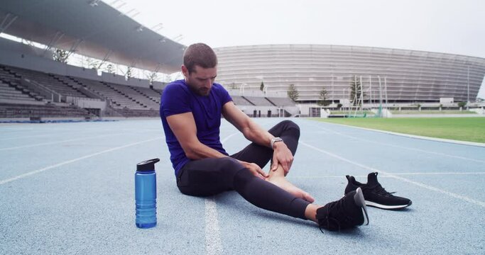 Man, sports and runner with a foot injury in workout, exercise or running track in stadium. Male athlete, feet and pain in ankle, leg or body wellness in field, training performance and health