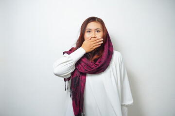 Oops! Surprised young Asian Muslim woman covering mouth with hands and staring at camera while standing against white background