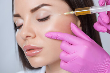 The doctor cosmetologist makes the Rejuvenating facial injections procedure for tightening and...
