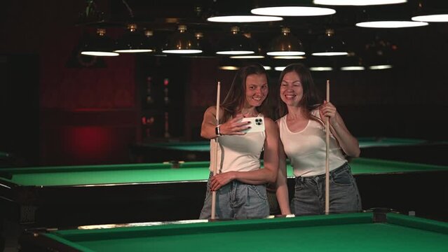 two women take pictures of themselves on a smartphone.women play billiards. slow motion video. High quality Full HD video recording