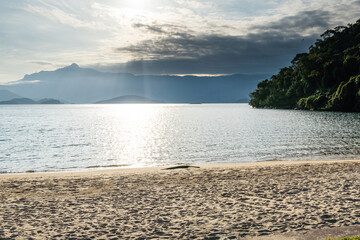 Beautiful beach in Angra do Reis, green coast of Rio de Janeiro. Tanguá Beach. Hills and mountains in the background on a sunny day. Crystal clear water. Late afternoon