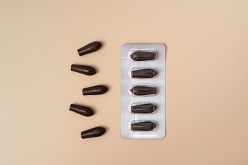 Blister with rectal suppositories on a beige plain background. Treatment of diseases and hemorrhoids by non-traditional methods, pharmacy and pharmacology concept.