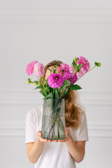 Vertical image of a young woman holding a bouquet of pink dahlia
