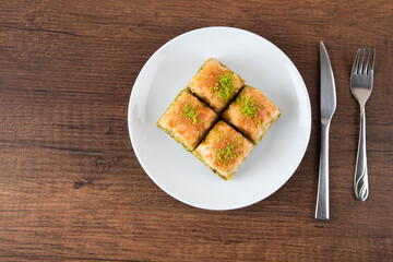 Turkish baklava with pistachio in plate.A plate baklava on wooden background,top view
