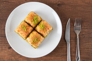 Turkish baklava with pistachio in plate.A plate baklava on wooden background,top view
