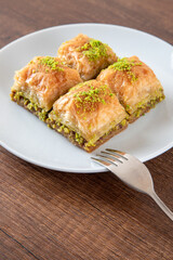 Turkish baklava with pistachio in plate.A plate baklava on wooden background,closeup