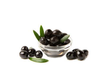 Black olives isolated on white background. Olives in a bowl. Olive tree leaves. Vegan. Ingredient for salad or pizza.
