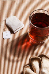 Natural medicine, reduce stress and improve immunity concept. Mushroom hot drink. Tea in glass mug with mushrooms on brown ribbed background. 