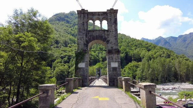 Drone flight over a wooden Tibetan suspended bridge that joins the river banks - view from the drone in Alagna Val Sesia Piedmont Alps mountains - travel concept journey in adventure natural trip 