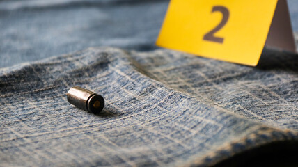Pistol bullet shells on blur blue jeans and number two display in background, concept for criminal and investigation. soft focus