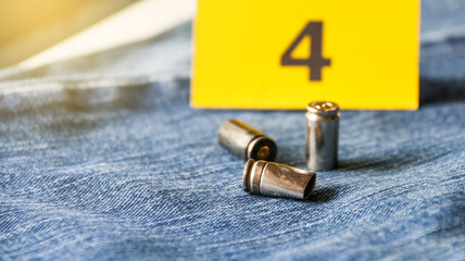 Pistol bullet shells on blur blue jeans and number four display in background, concept for criminal...