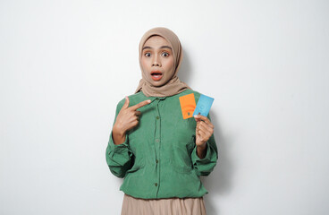 Smiling young Asian Muslim woman dressed in green shirt holding credit card, online shopping isolated over white background
