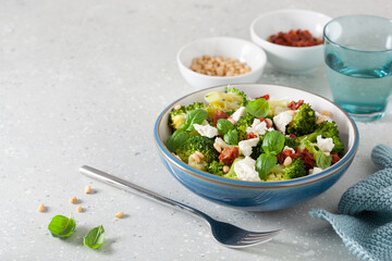 healthy broccoli salad with feta cheese sun dried tomatoes pine nuts. vegetarian low carb keto diet