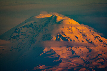 Sunlight on the snowy peak in clouds. Beautiful sunset at Mount Rainier National Park