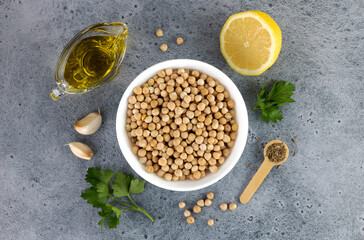 Ingredients for classic hummus: chickpeas, olive oil, parsley, lemon and garlic on a blue...