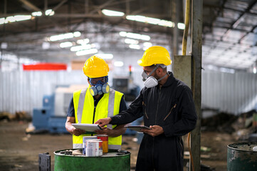 Two officers wearing gas masks, holding tablet and book, inspect the chemical spill site in an industrial warehouse to assess the damage, wearing gas masks, inspecting and evaluating toxicity of leak.