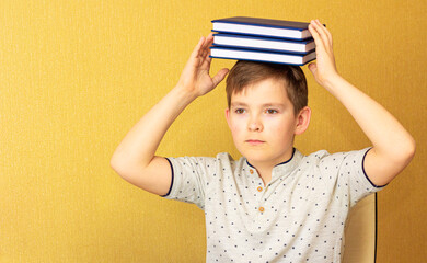 A stack of books on the boy's head. Fun & Meditation. Back to School