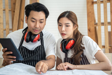 Two asian carpenter working in their workshop. They using tablet to work and search information in workshop.